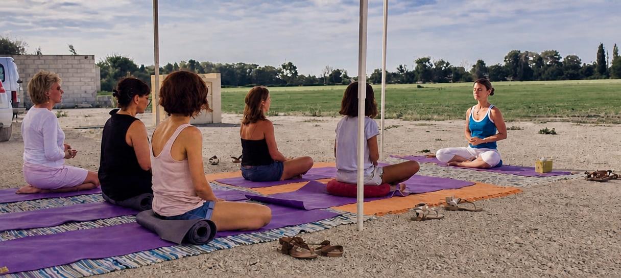Cours de yoga Kundalini en groupe, en plein air, assis sur des tapis